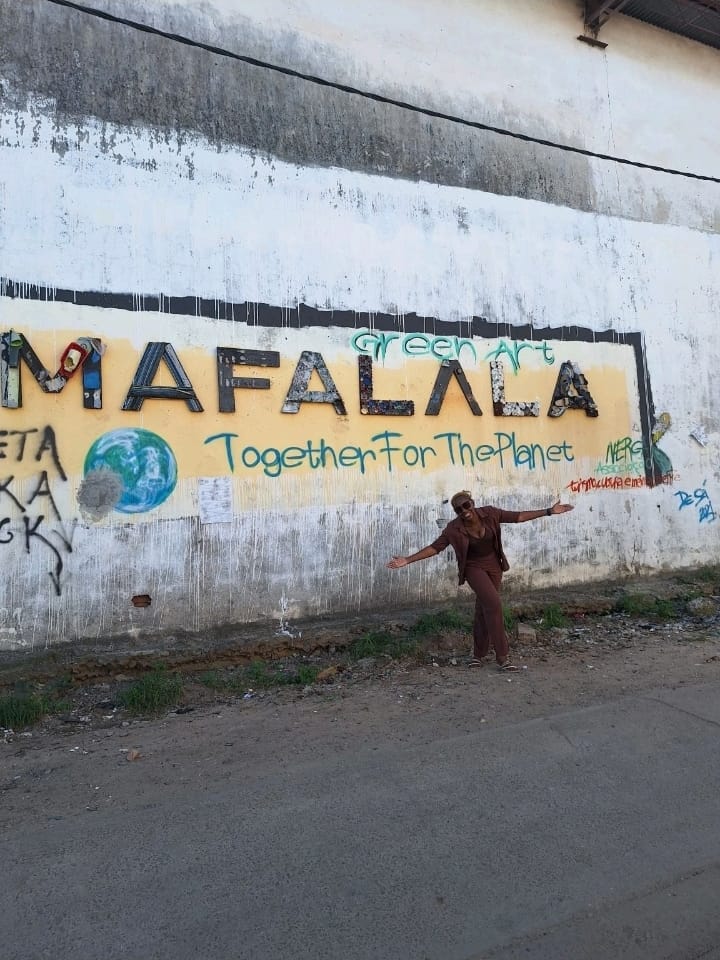 Eunice posing beside the Mafalala Green Art mural in Maputo