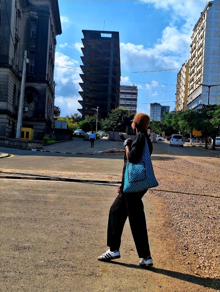 Eunice crossing a Maputo street carrying a bright blue handmade bag