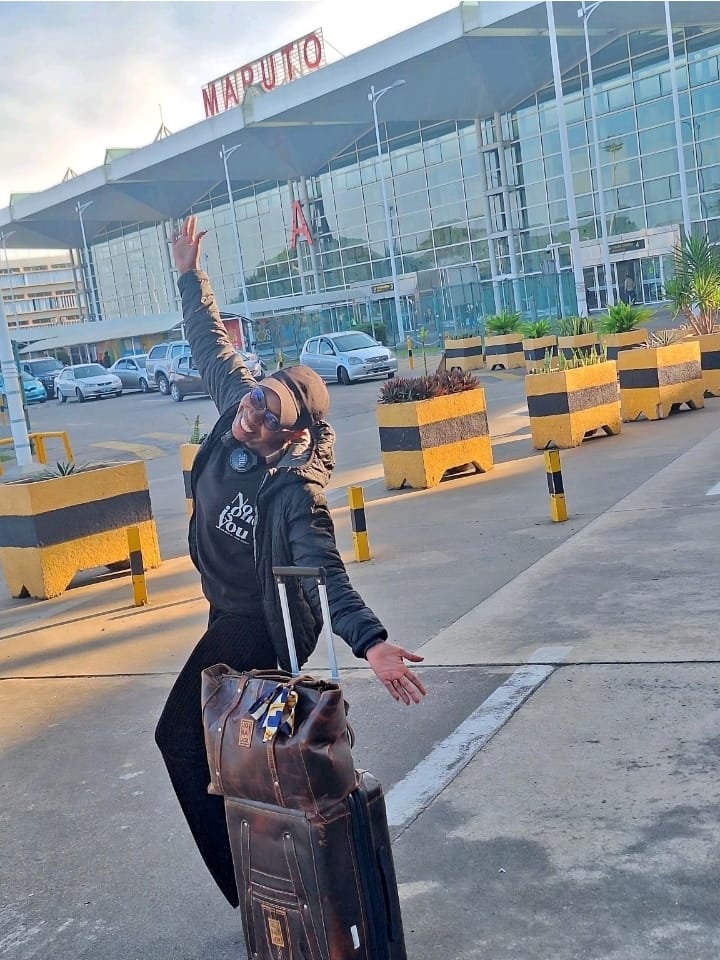 Eunice arriving at Maputo International Airport with her luggage, arms raised in celebration
